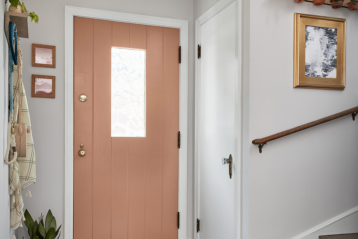 Terra cotta-toned Canyon Earth door in small entryway with coat closet and stairs.