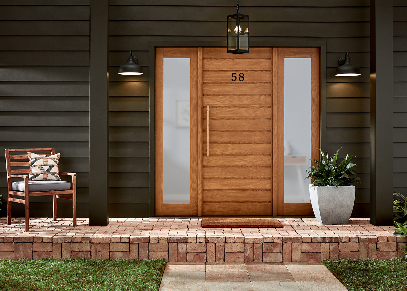 Dark Fired paint creates a moody and modern aesthetic on a home exterior with a lighter wood door, chair and planter.